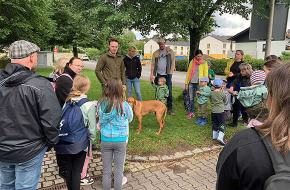 Eltern und Kinder lauschen gespannt was der Förster Marcel Waffler und sein Hund Arko über den Wald zu berichten haben. (MGH/ Marika Philipp)