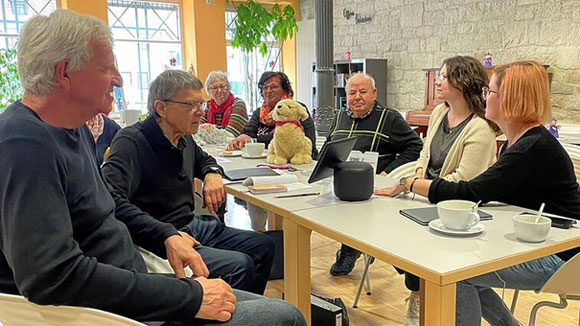  Foto: Peter Schmieder | Das Mehrgenerationenhaus in Haßfurt ist einer von 42 KI-Lernorten. In der Rentenschmiede experimentiert Besucher Werner Burger (Zweiter von links) mit einem Sprachassistenten.